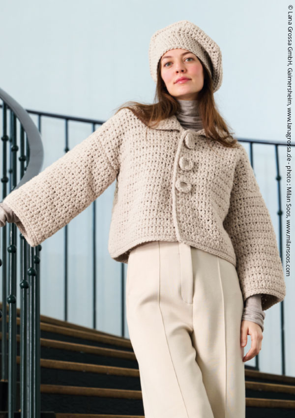 Femme portant une veste en crochet beige à trois boutons et pantalon assorti, sur un escalier extérieur.